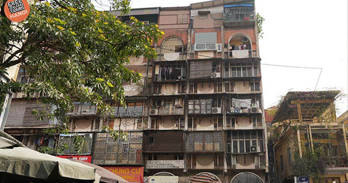 Collective housing block with plants, balconies, and street vendors.